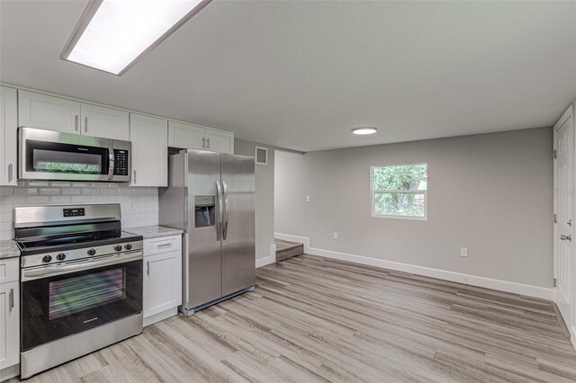 kitchen featuring stainless steel appliances, light hardwood / wood-style flooring, and white cabinets