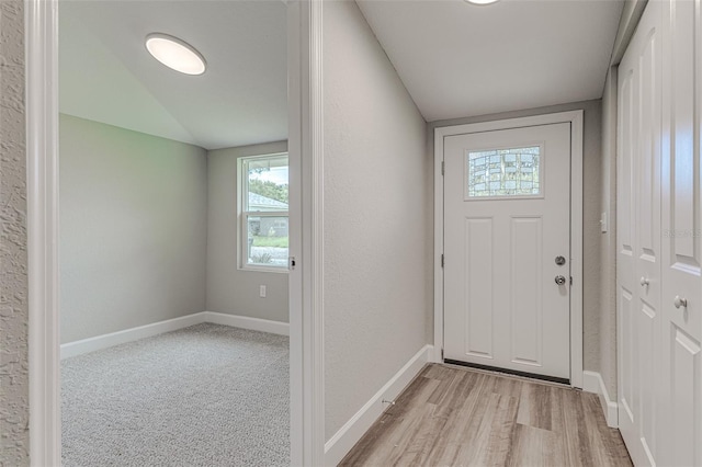 entrance foyer with lofted ceiling, light wood-style flooring, baseboards, and a textured wall