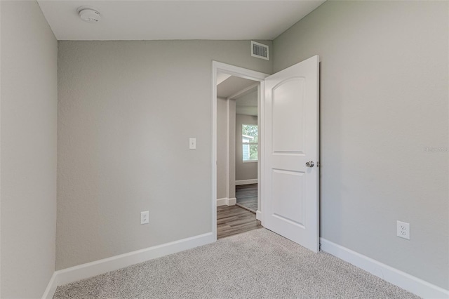 spare room featuring light carpet, visible vents, baseboards, and vaulted ceiling