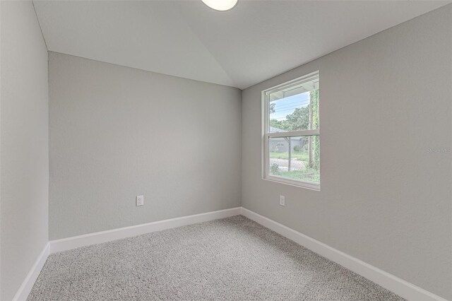 carpeted spare room featuring vaulted ceiling