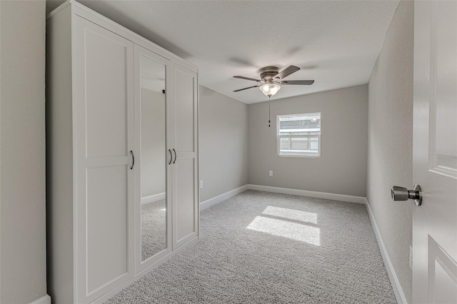 unfurnished bedroom with a ceiling fan, baseboards, a textured ceiling, and light colored carpet