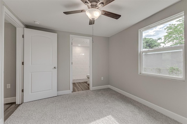 unfurnished bedroom featuring carpet, ensuite bath, a ceiling fan, and baseboards