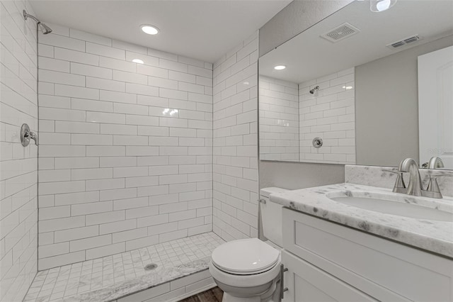 bathroom featuring vanity, tiled shower, and toilet