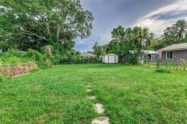 view of yard featuring a storage shed, an outdoor structure, and fence