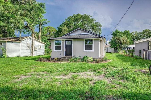 view of front facade featuring an outbuilding, board and batten siding, a front yard, fence, and a shed