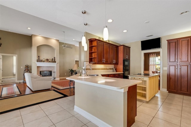 kitchen with sink, light tile patterned flooring, a fireplace, kitchen peninsula, and ceiling fan