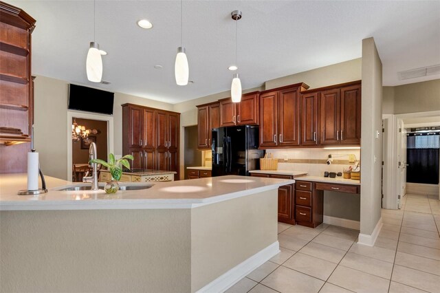 kitchen with a center island with sink, light tile patterned floors, sink, black refrigerator with ice dispenser, and decorative light fixtures