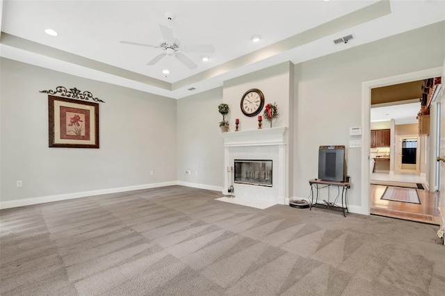 unfurnished living room with carpet, ceiling fan, and a raised ceiling