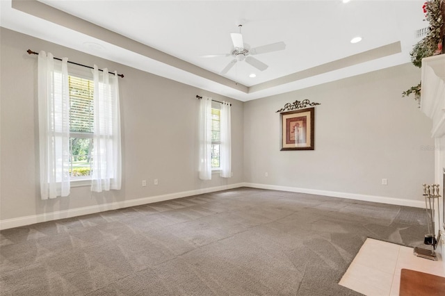 carpeted spare room featuring ceiling fan and a tray ceiling