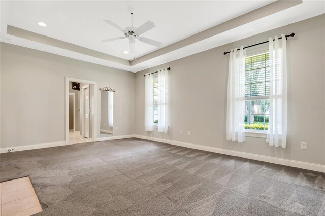 spare room with carpet flooring, ceiling fan, and a raised ceiling