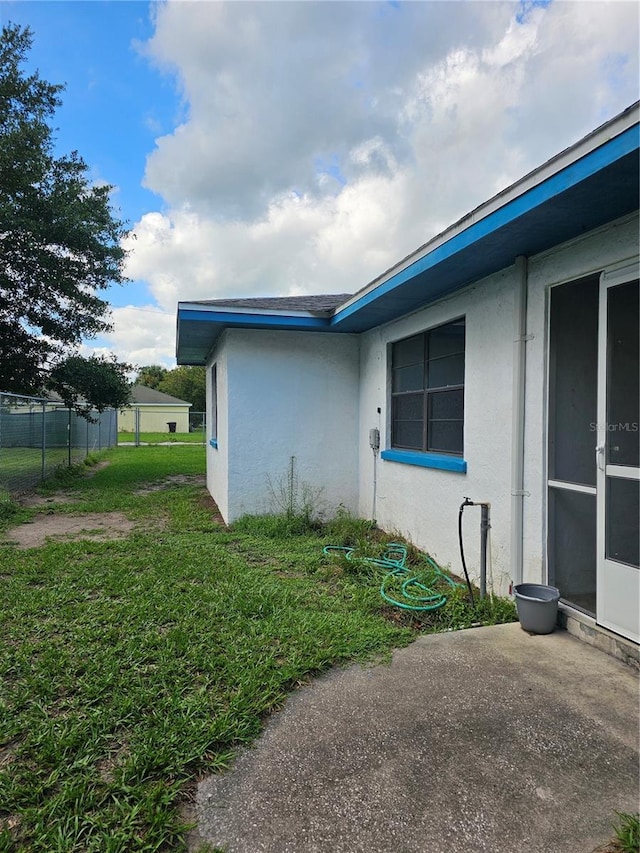 view of side of property with a yard, fence, and stucco siding