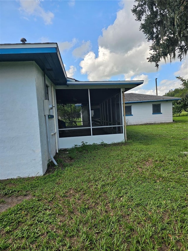 view of property exterior featuring a sunroom and a yard