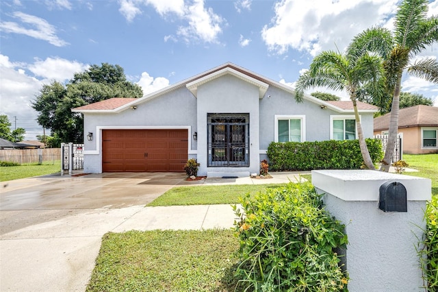 view of front of house featuring stucco siding, driveway, an attached garage, and fence