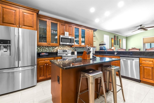 kitchen featuring light tile patterned floors, a kitchen breakfast bar, a kitchen island, and appliances with stainless steel finishes