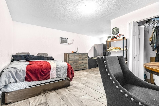 bedroom with a wall unit AC and a textured ceiling