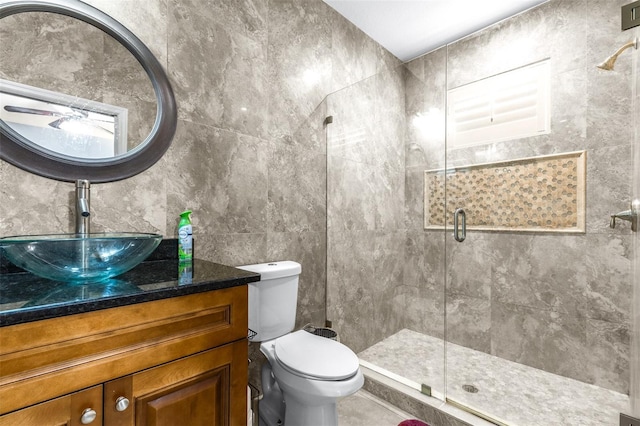 full bathroom featuring toilet, tile walls, a stall shower, and vanity