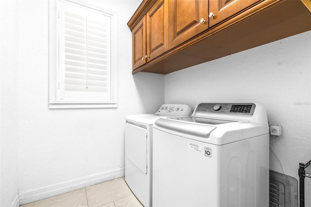 washroom featuring light tile patterned floors, cabinet space, baseboards, and washer and clothes dryer