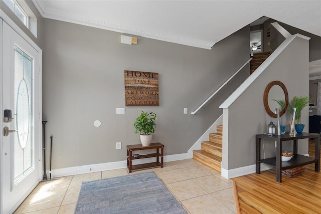 foyer entrance featuring stairs, baseboards, ornamental molding, and light tile patterned flooring