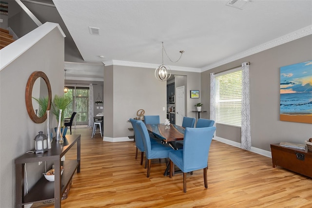 dining area with ornamental molding, light hardwood / wood-style floors, and a chandelier