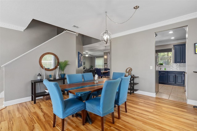 dining space with ceiling fan with notable chandelier, crown molding, and light hardwood / wood-style flooring