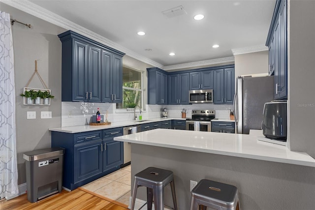 kitchen with a sink, light countertops, appliances with stainless steel finishes, and blue cabinetry