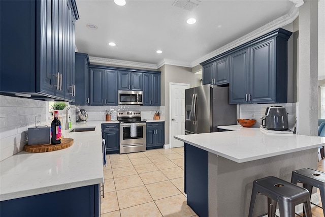 kitchen with visible vents, a breakfast bar, stainless steel appliances, blue cabinetry, and a sink