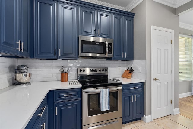 kitchen with appliances with stainless steel finishes, blue cabinets, decorative backsplash, and light tile patterned floors