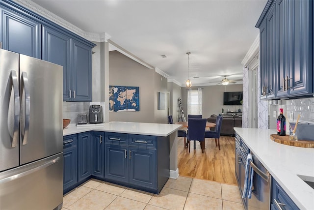 kitchen with appliances with stainless steel finishes, blue cabinetry, crown molding, kitchen peninsula, and decorative backsplash