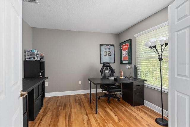 office space with a textured ceiling, baseboards, and wood finished floors