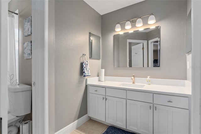 bathroom with toilet, vanity, and tile patterned floors