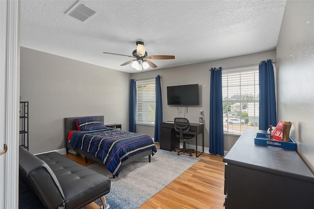 bedroom with ceiling fan, hardwood / wood-style floors, and a textured ceiling