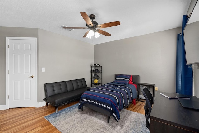 bedroom featuring visible vents, ceiling fan, a textured ceiling, wood finished floors, and baseboards