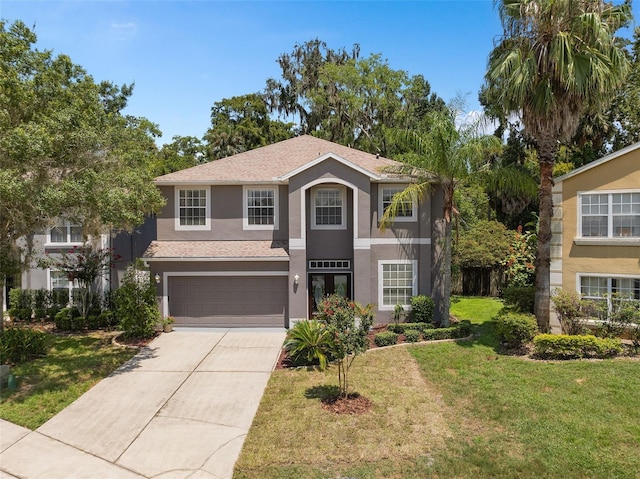 view of front of house featuring a garage, driveway, a front yard, and stucco siding