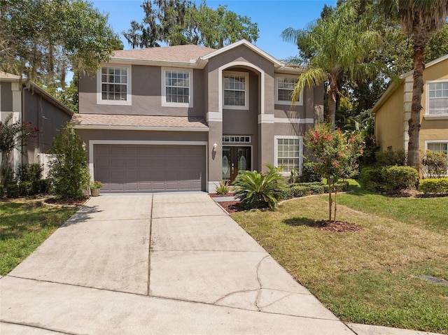 traditional-style house featuring driveway, an attached garage, a front lawn, and stucco siding