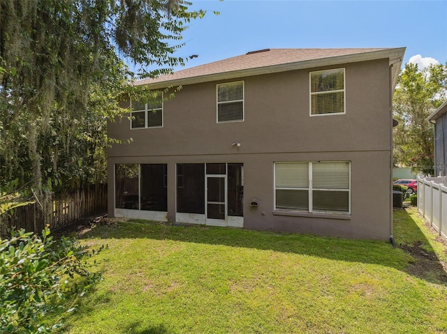 back of property with a sunroom, a fenced backyard, a lawn, and stucco siding