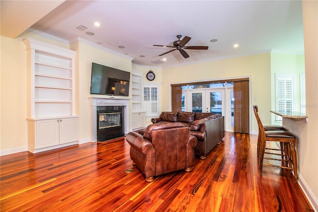 living room with a fireplace, french doors, dark hardwood / wood-style flooring, ceiling fan, and ornamental molding