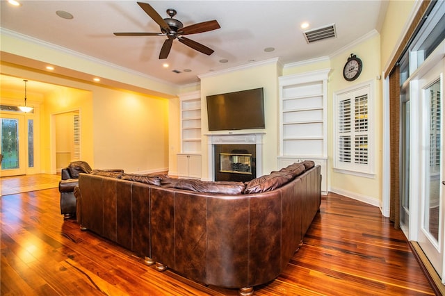 living room featuring dark wood-type flooring, ceiling fan, ornamental molding, and a multi sided fireplace