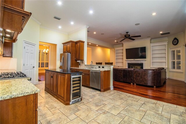 kitchen with custom exhaust hood, beverage cooler, appliances with stainless steel finishes, a center island, and ceiling fan