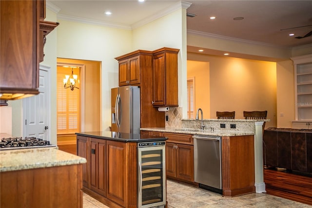 kitchen with beverage cooler, sink, a center island, light stone countertops, and appliances with stainless steel finishes