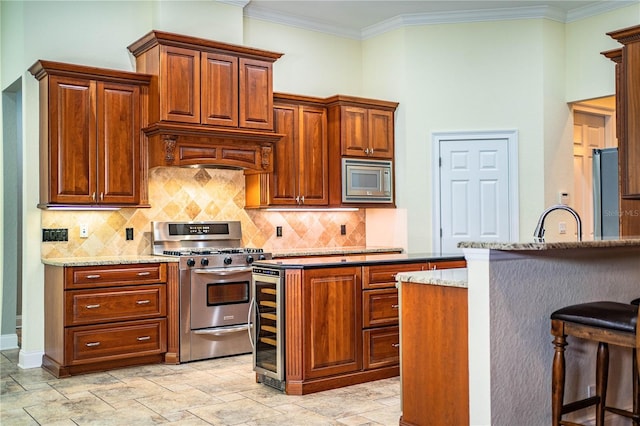 kitchen with a kitchen breakfast bar, beverage cooler, appliances with stainless steel finishes, sink, and light stone counters