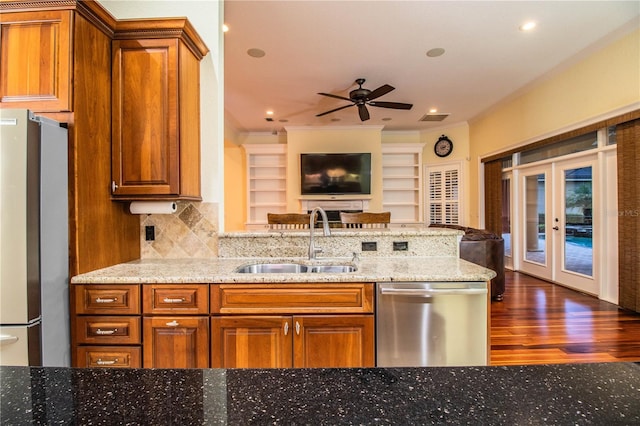 kitchen with dark wood-type flooring, stainless steel appliances, sink, ceiling fan, and light stone counters