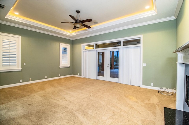 unfurnished living room featuring crown molding, a raised ceiling, ceiling fan, and french doors