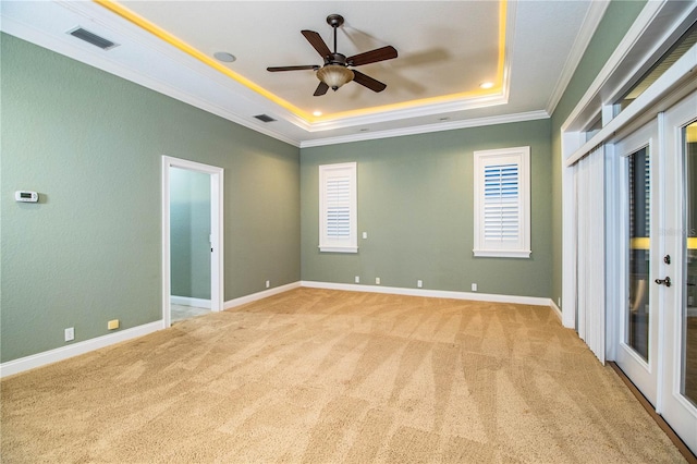 spare room featuring crown molding, french doors, light colored carpet, a tray ceiling, and ceiling fan