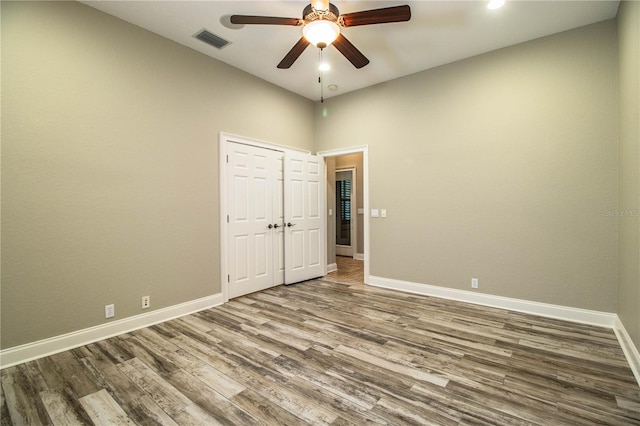 unfurnished bedroom with wood-type flooring, ceiling fan, and a closet