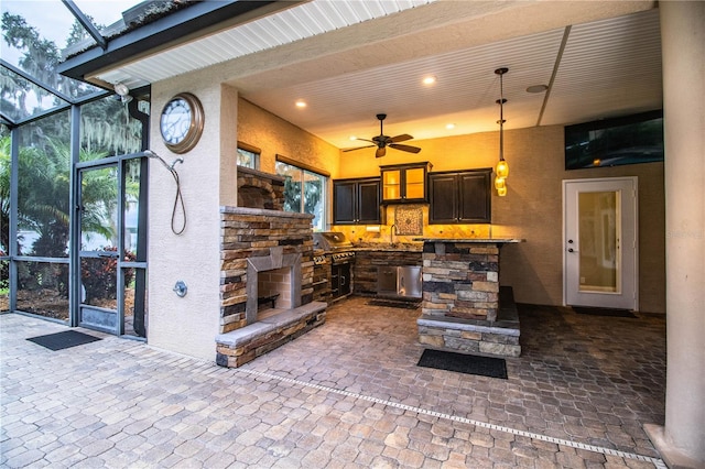 view of patio / terrace featuring ceiling fan, sink, a lanai, and a fireplace