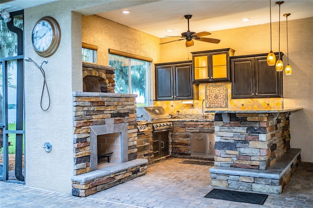 kitchen featuring light stone countertops, decorative light fixtures, a fireplace, tasteful backsplash, and ceiling fan