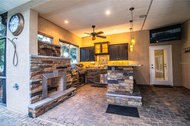 interior space featuring light stone countertops, decorative light fixtures, a fireplace, ceiling fan, and dark brown cabinetry