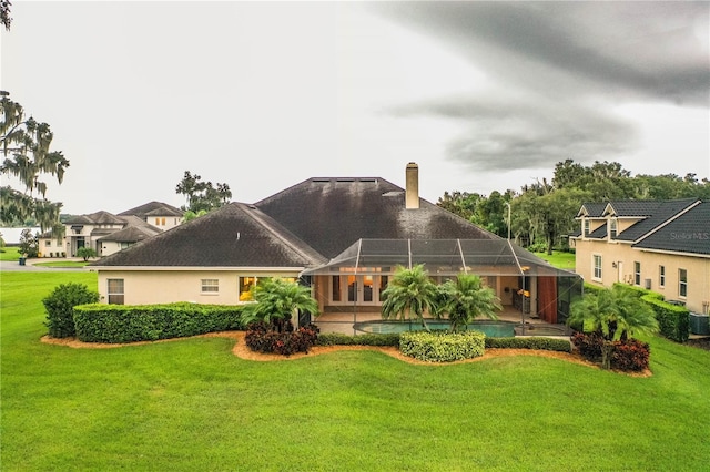 rear view of property with glass enclosure, central air condition unit, and a lawn