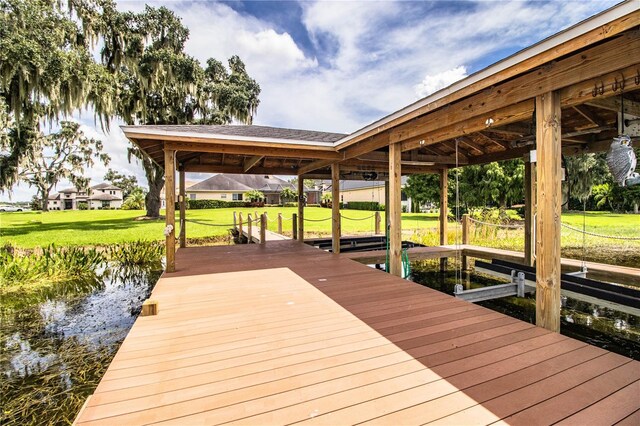 view of dock with a lawn and a water view