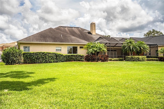 rear view of property featuring a lanai and a lawn